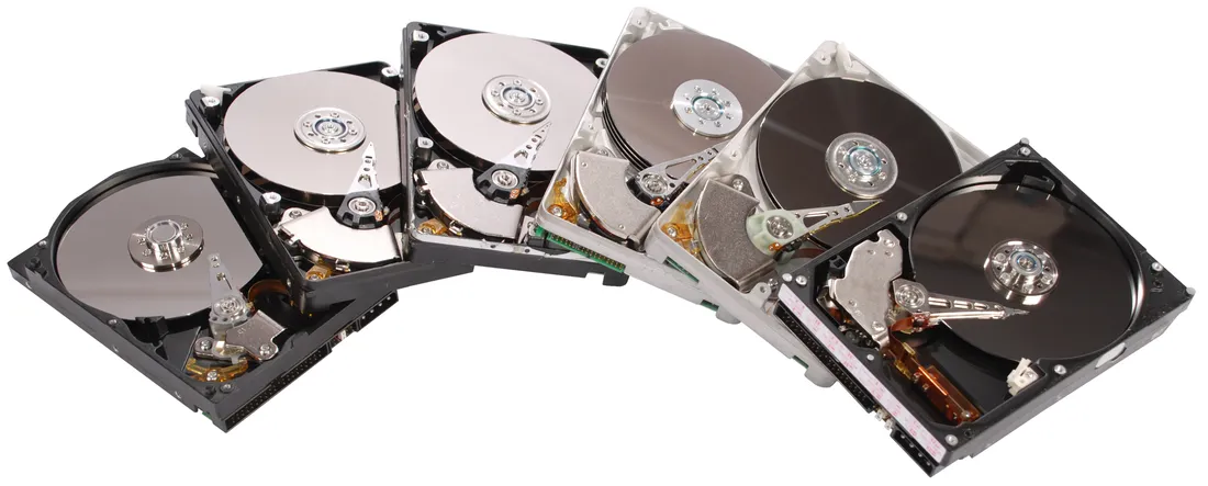 Six opened hard drives of different makes and ages, fanned out side by side